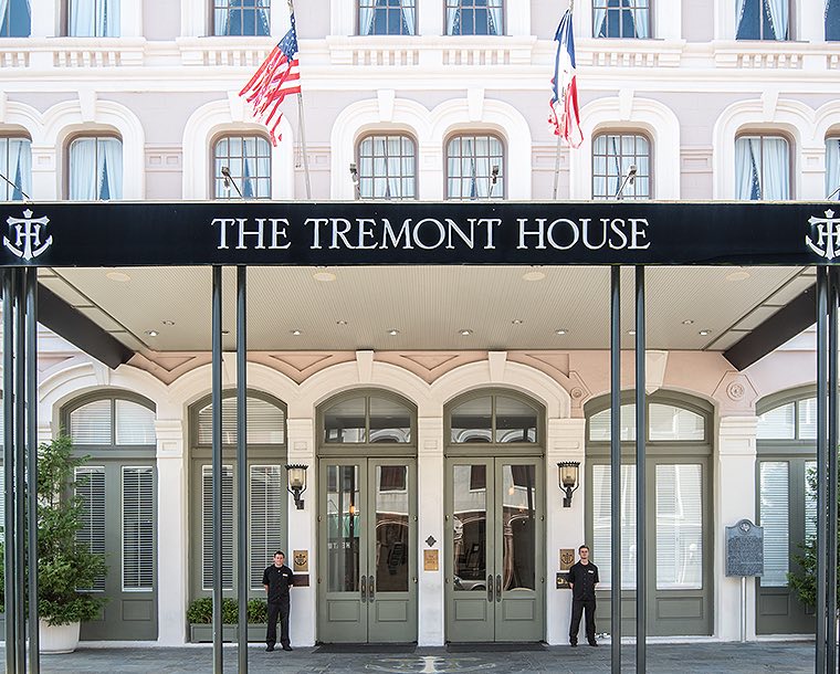 hotel doormen standing at entrance to hotel lobby under black awning