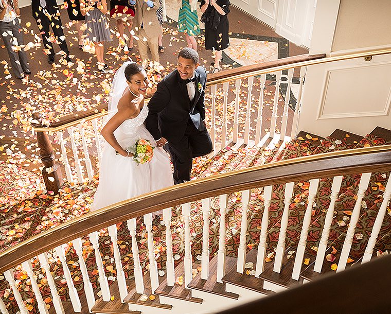 newly wed young couple laughing and walking up red carpet stairs