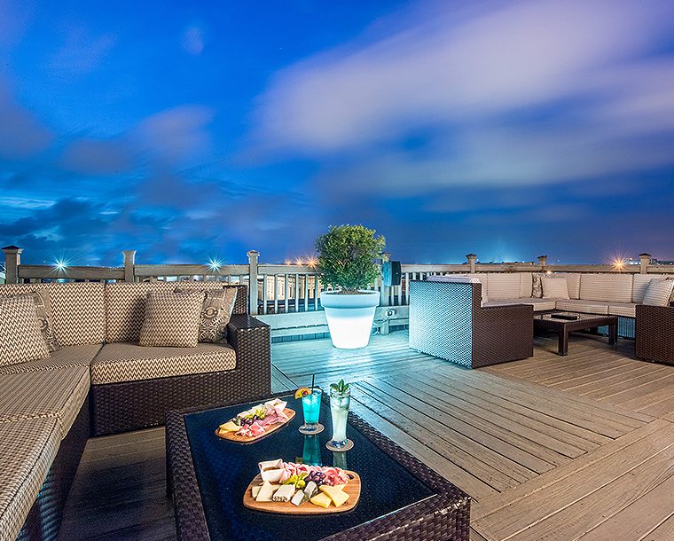 rooftop bar at night with seating and meat and cheese boards