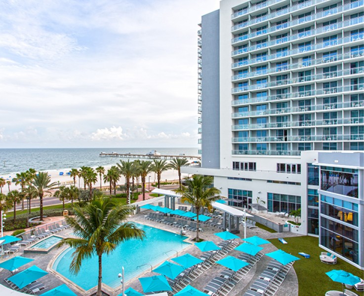 swimming pool area with palm trees and pool umbrellas