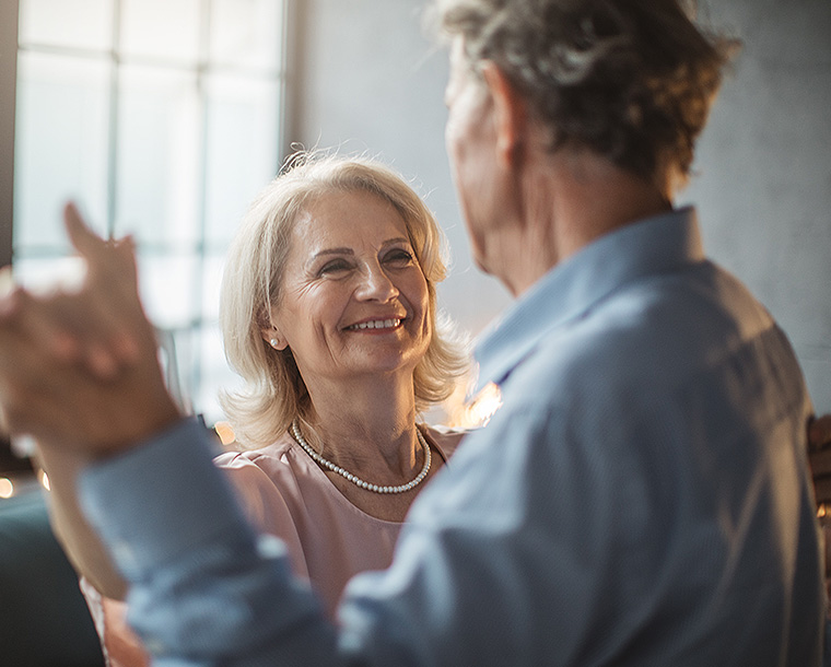 elderly couple dancing against a brightly lit window