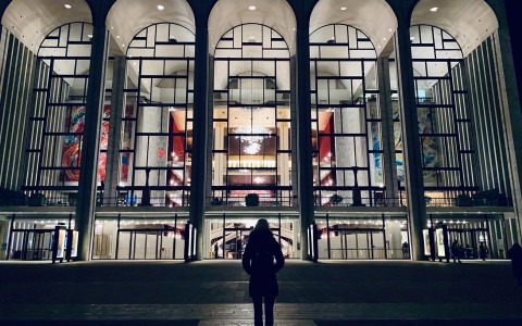 woman standing in front of the MoMA at night 