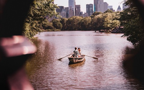two people on a canoe in the river with trees in the background 
