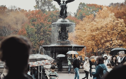 fountain with an angel and a crowd of people surrounding it 