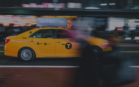 view of a new york city street with only a taxi cab in focus 