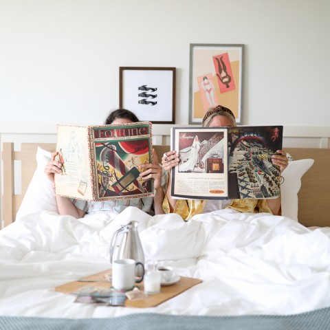 two girls reading a magazine in bed