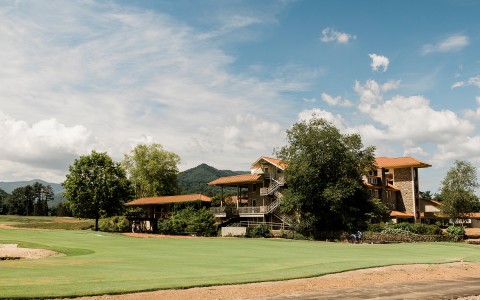 a large multi story building located next to the golf course during the day