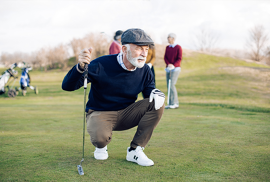 older gentleman kneeling on a golf course