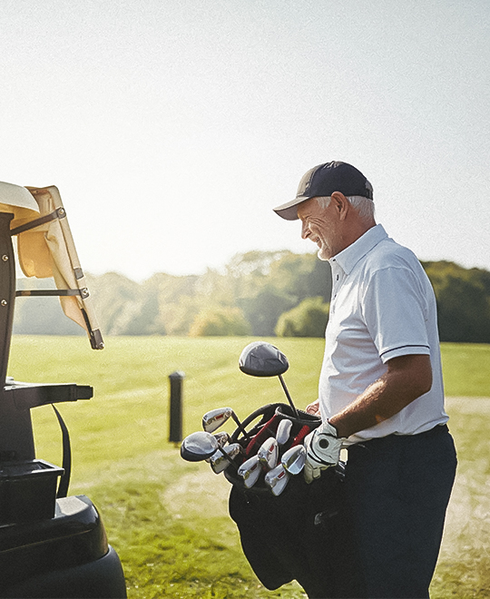 an older gentlemen holding his golf bag on the course