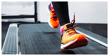 Person with neon orange sneakers running on a treadmill