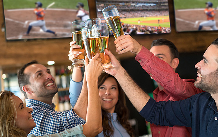 group of friends clicking beer glasses in a bar watching baseball