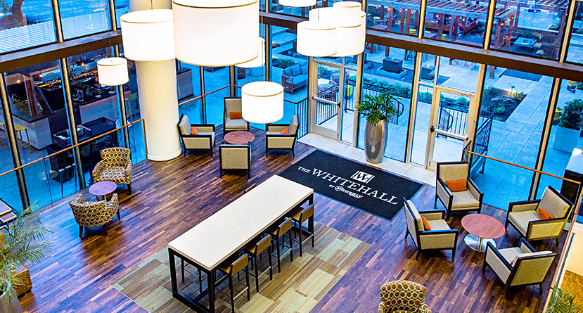 hotel lobby entrance features floor to ceiling glass walls and several seating areas