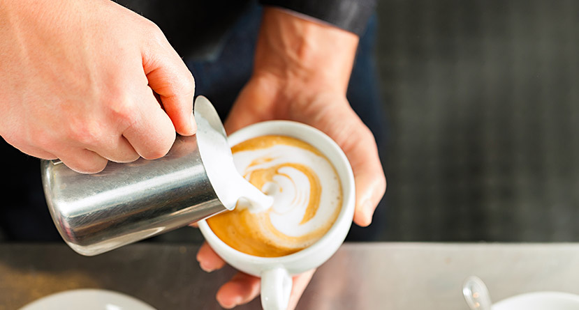 barista poring froth in cappuccino