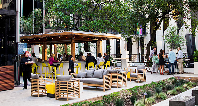 Exterior courtyard dining of Part and Parcel. Pergola with long tables and lounge seating