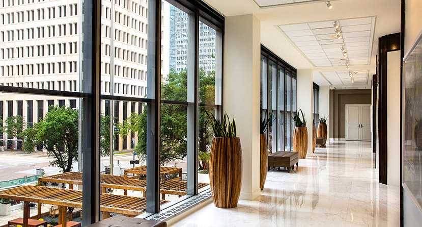 lobby interior with floor to ceiling windows. large wooden plant holders flank the hall way