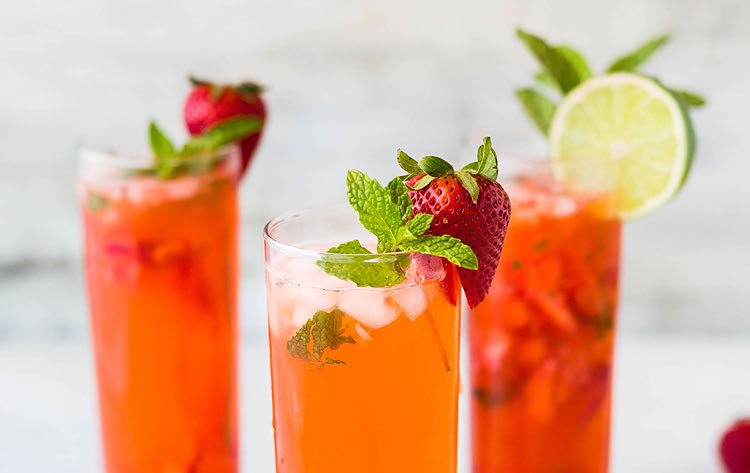 three bright colored beverages with fruit in them