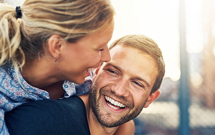 women hugging man from behind giggling