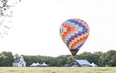 Hot air balloon in a grass field and behind there is a chapel