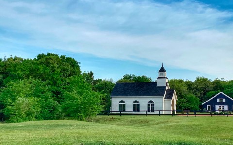 church and home in a flat landscape surrounded by trees