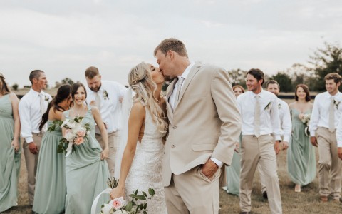 couple kissing in a wedding and people looking at them