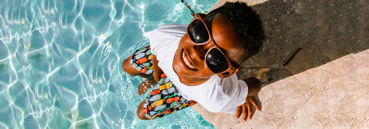 up view of a kid seating at the edge of a pool looking up