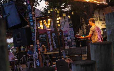 guy singing and playing guitar on the Tiki Hut stage outdoors