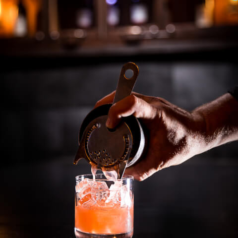 Person pouring orange cocktail