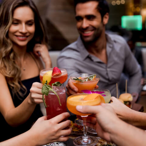 Group of friends toasting with colorful cocktails