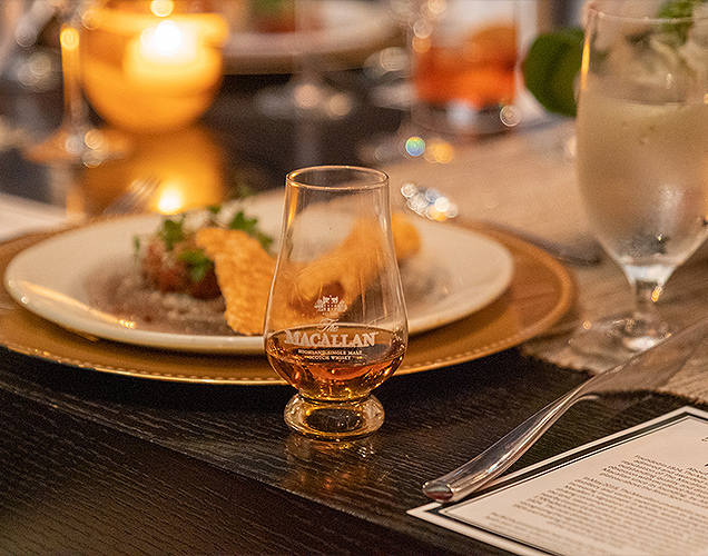 Macallan Event in the evening, with a plate of food and a candle on the table.
