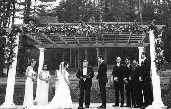 black and witebride and groom up at alter flanked by bridal party