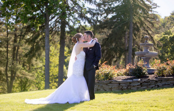 bride and groom kissing on lawn in front of fountain