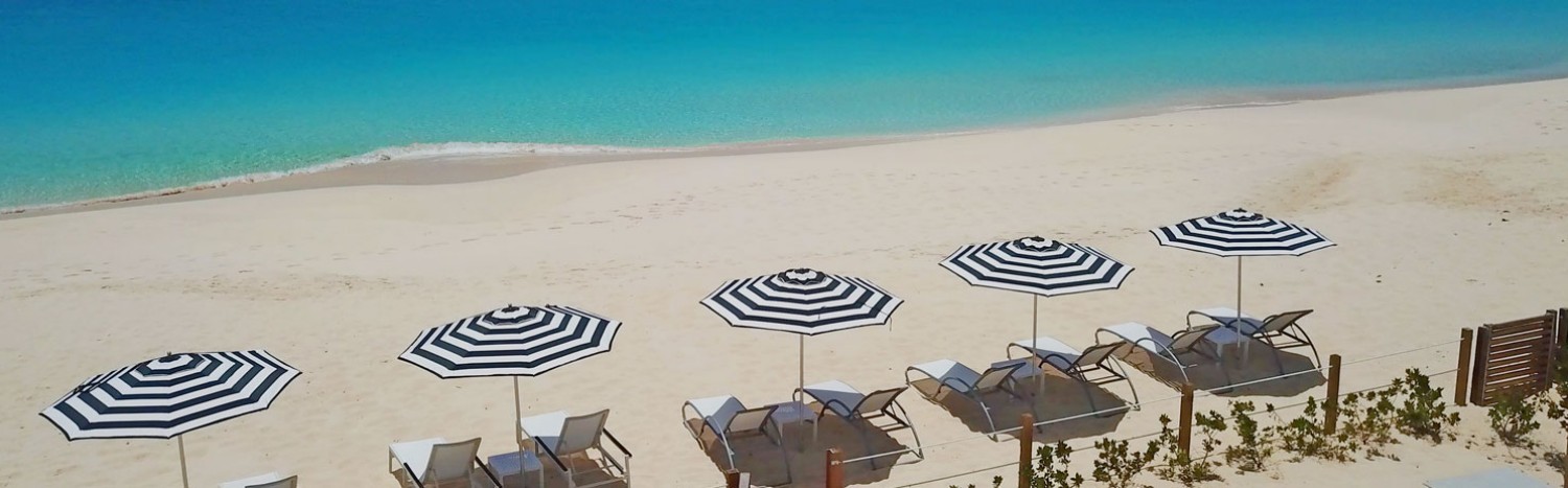 white sand beach with lounge chairs and parasols