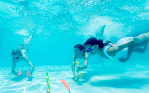 three kids playing under water in a pool