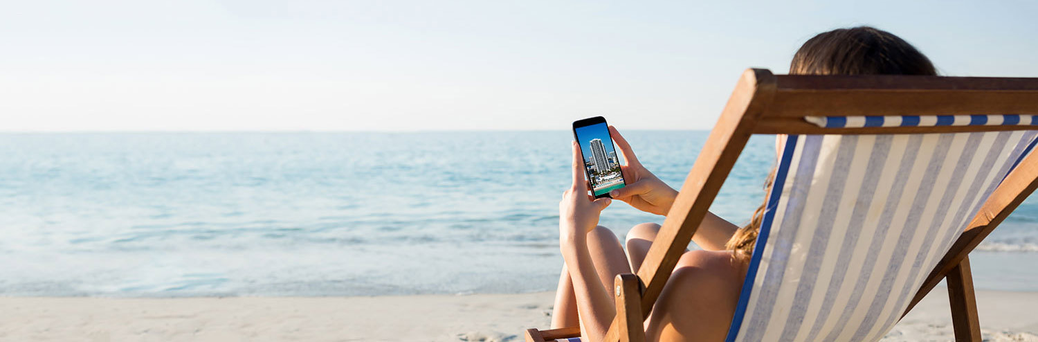 woman sitting at the beach looking at her phone
