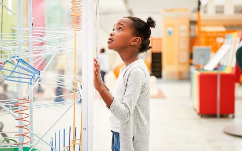 little girl looking at an art sculpture