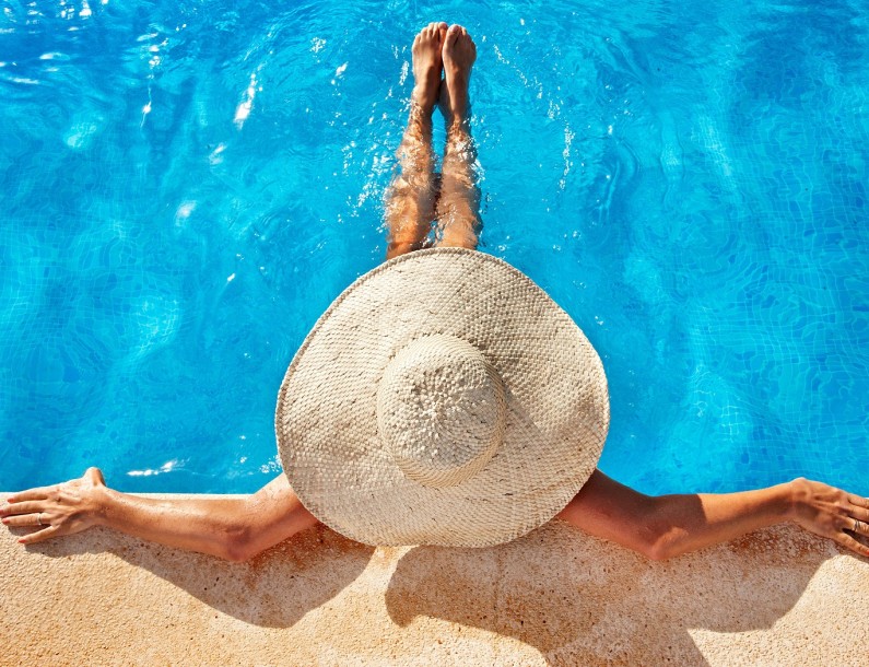 woman wearing a large sunhat sitting in the pool