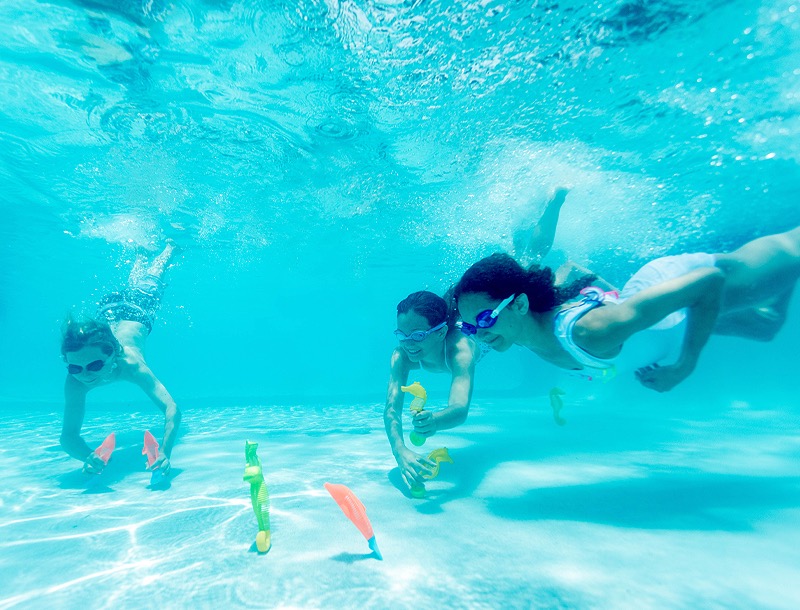 three kids playing under water in a pool
