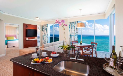 a kitchen and dining room of a hotel suite overlooking the ocean
