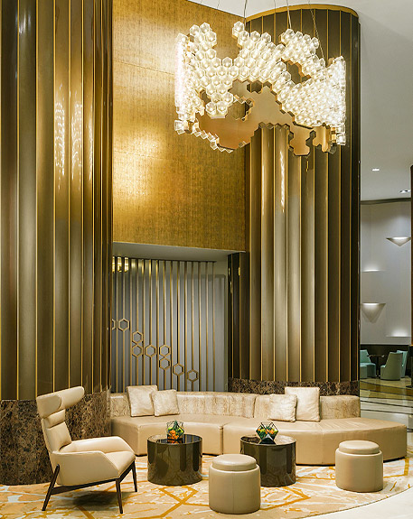 an elegant lobby with a detailed chandelier with a gold theme