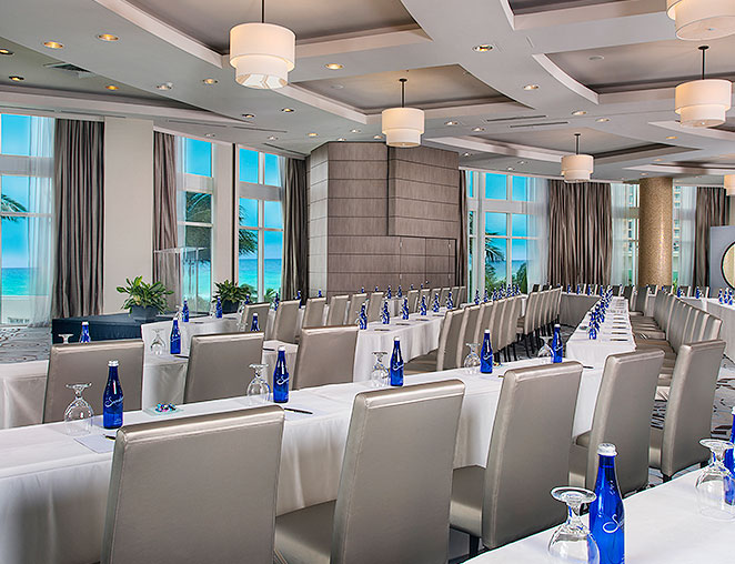 a large conference room with floor to ceiling windows overlooking the beach