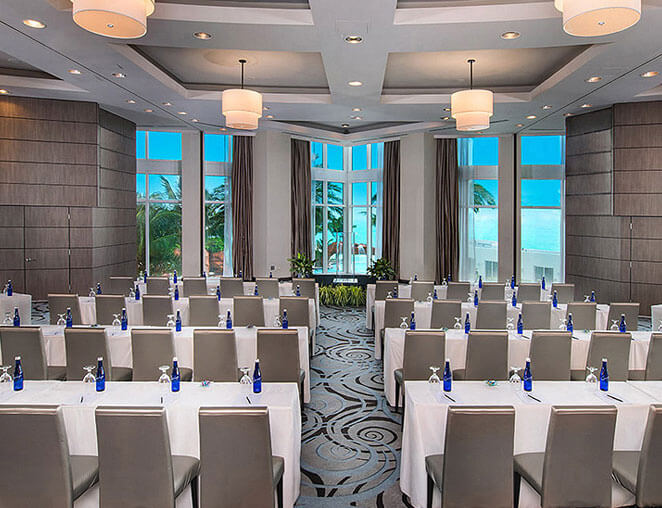 a large conference room with floor to ceiling windows overlooking the beach
