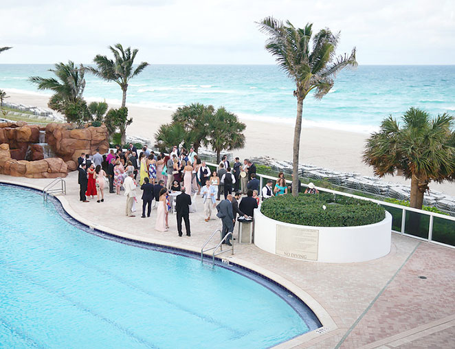 a group of people gathered by the pool overlooking the beach
