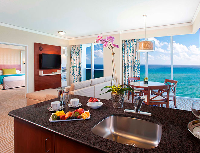 a room with a kitchen and dining room with views of the ocean