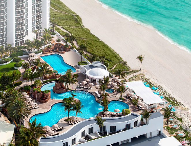 a birds eye view of a hotel with two pools on the beach