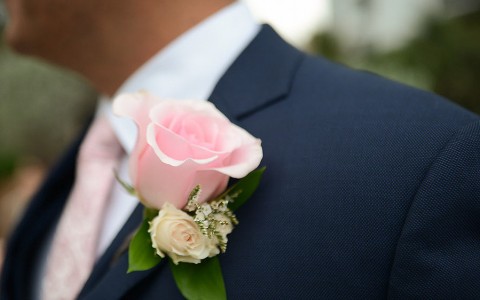 close up of a flower on a groom's lapel