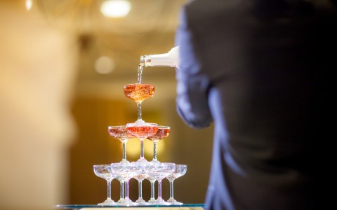 man pouring champagne in a tower of flutes