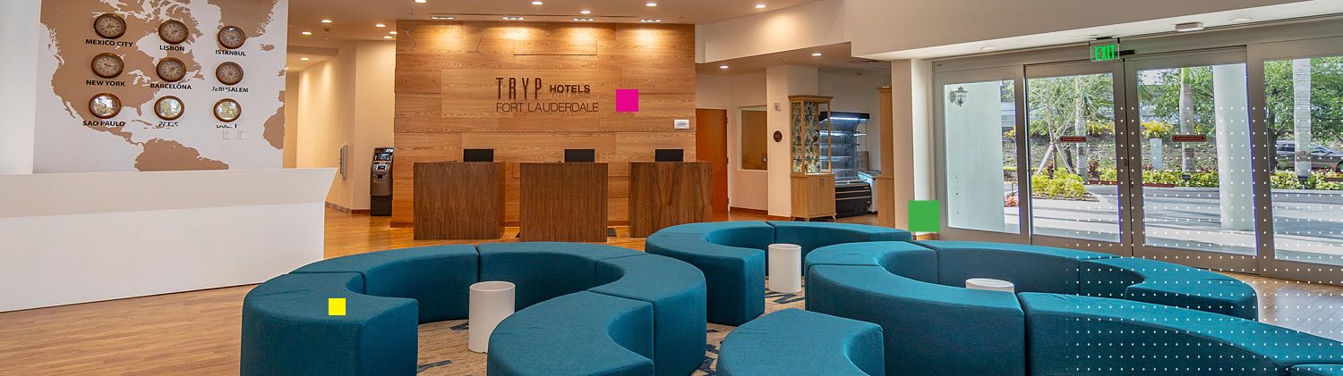 Lobby area with modern turuoise couch & time zone clocks next to front lobby