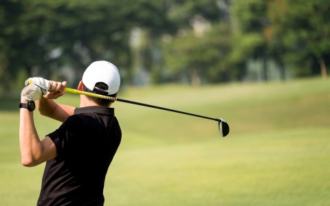 golfer with golf club swinging up behind their neck