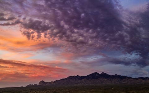 沙漠和远处的山，粉红色，橙色和紫色的天空