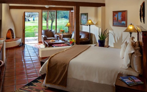 客房有床，一个壁炉，和一扇门通向露台和高尔夫球场